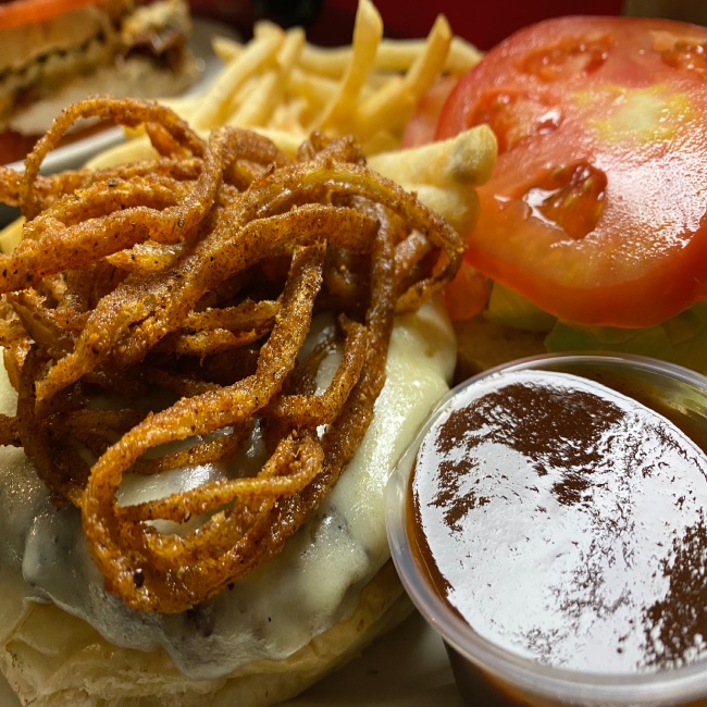 A burger with onion rings and fries on a plate.