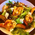 A salad with shrimp, peaches and goat cheese.