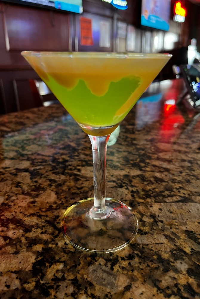 A green martini sitting on top of a bar.