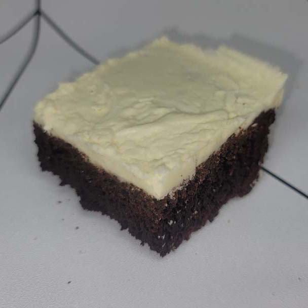 A piece of chocolate cake with cream cheese frosting.