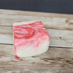 A piece of red and white soap on a wooden table.