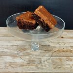 Two brownies on a clear glass plate.