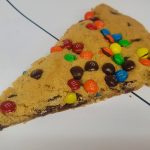 A piece of cookie with m & m's on it.