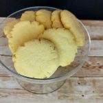 Lemon cookies in a glass bowl on a wooden table.