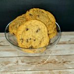 Chocolate chip cookies in a glass bowl on a wooden table.