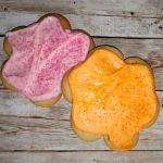 Two frosted sugar cookies on a wooden table.