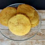 Cornbread cookies in a glass bowl on a wooden table.