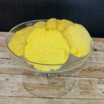 Yellow sugar cookies in a glass bowl on top of a wooden table.