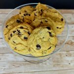 Chocolate chip cookies in a glass bowl on a wooden table.
