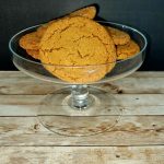 Ginger cookies in a glass bowl on a wooden table.