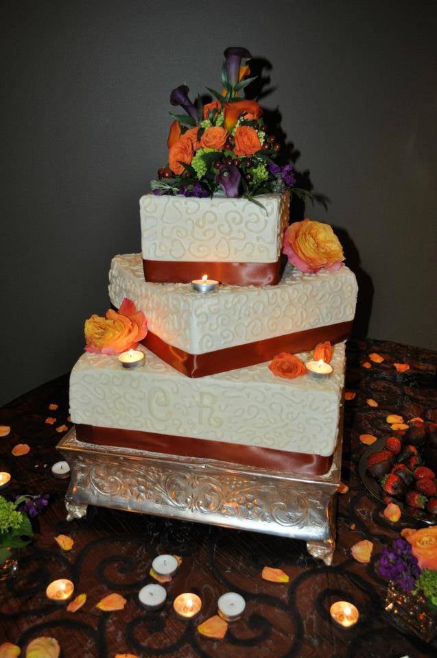 Custom Three tier wedding cake with orange flowers and candles. Made by Nan's Nummies