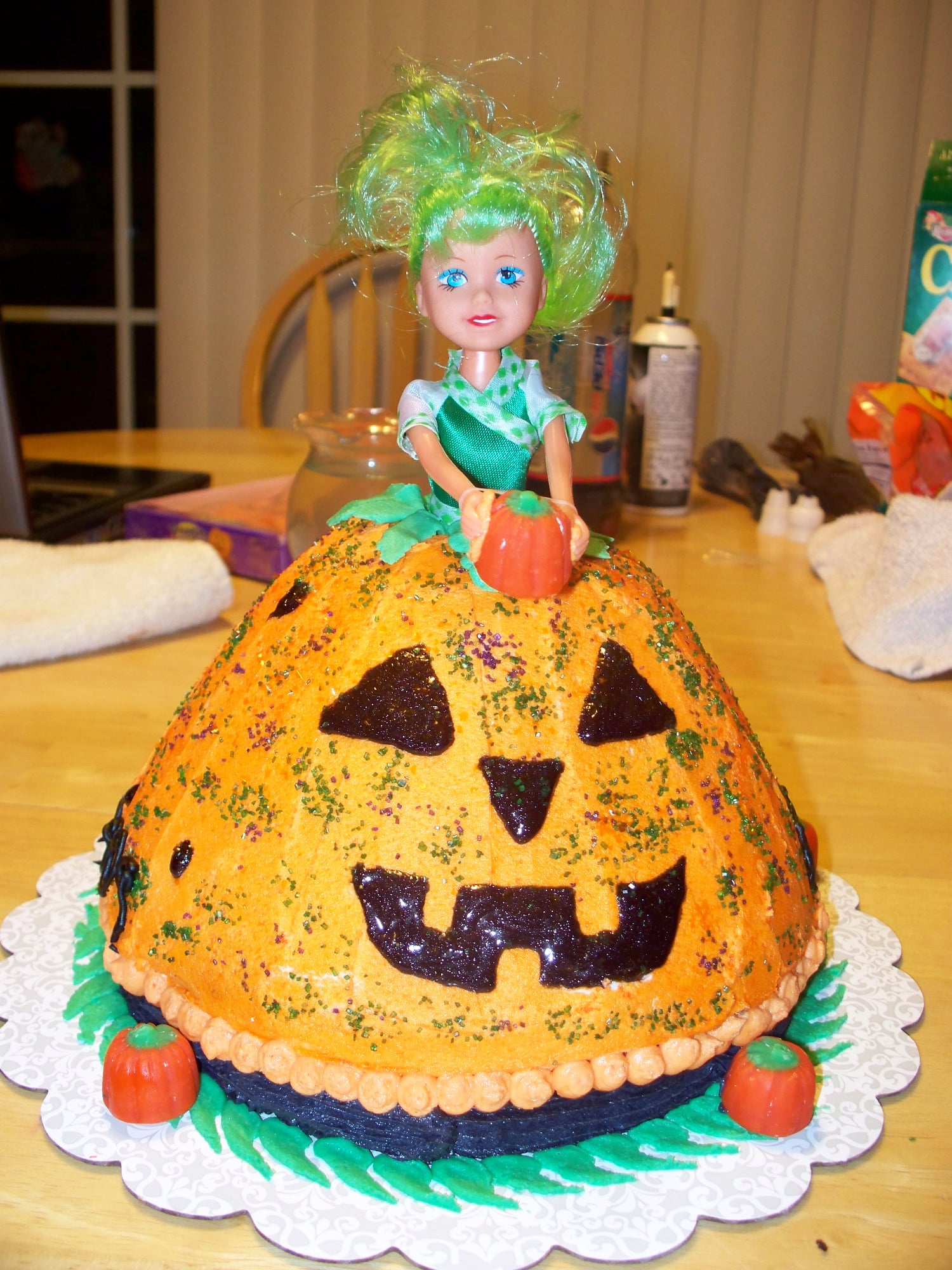 A doll sitting on top of a custom pumpkin cake. Made by Nan's Nummies