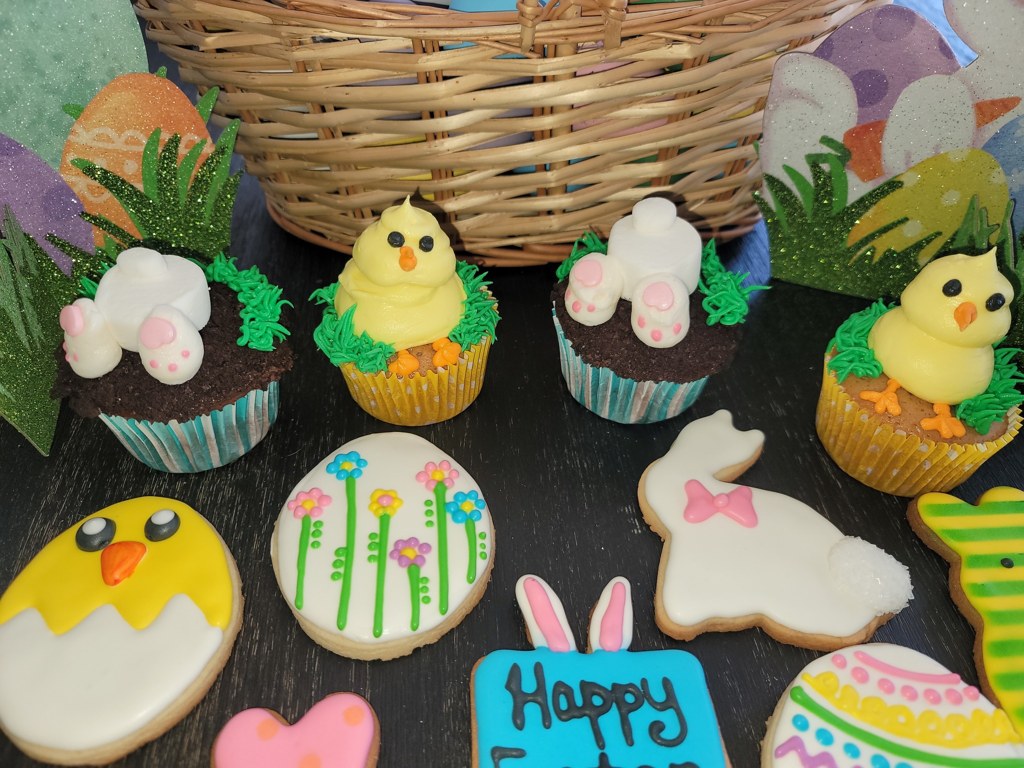 A basket of easter cookies decorated with bunnies and chicks.