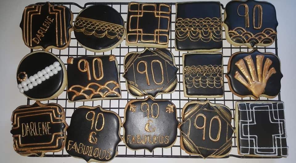 A rack of black and gold cookies on a cooling rack.
