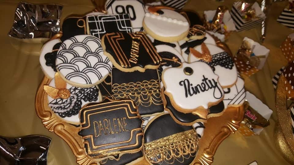 A tray of black and gold cookies on a table.