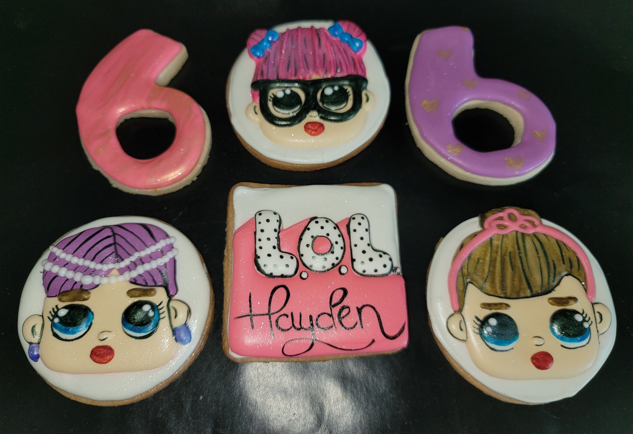 A group of cookies decorated with lol doll faces.