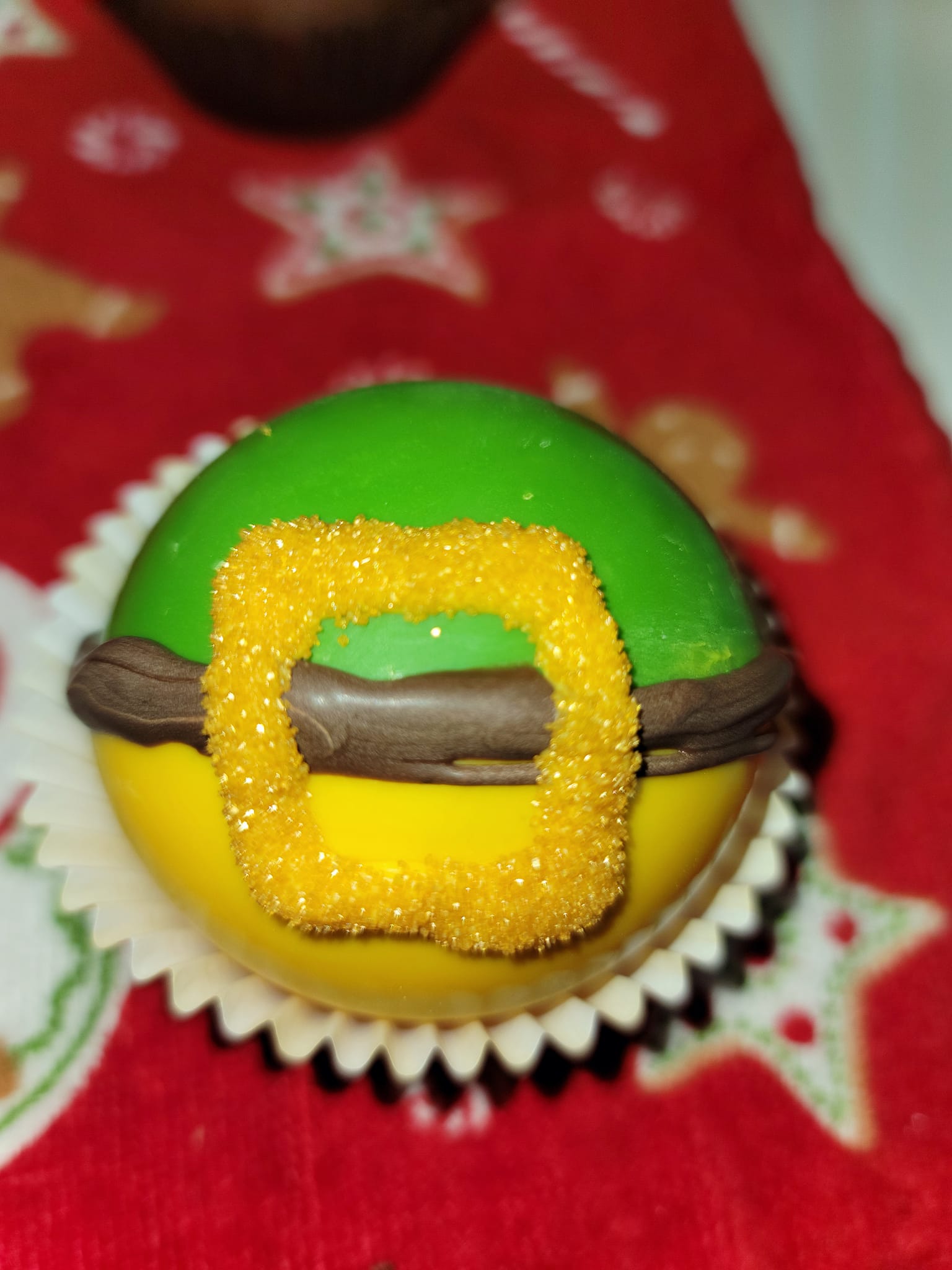 A green and yellow cupcake with a santa hat on it.