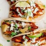 Mexican chicken tacos on a wooden cutting board.