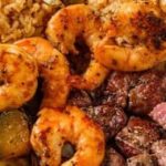 A plate with steak, shrimp, rice and vegetables.