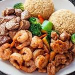 A plate with shrimp, rice and vegetables on it.