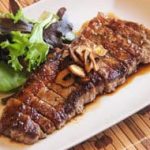 A plate with a steak and salad on it.