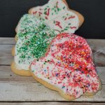 Three cookies decorated with sprinkles on a wooden table.