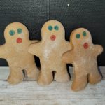 Three gingerbread men sitting on a wooden table.