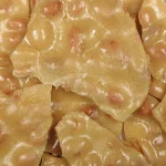 A pile of peanut brittle on a white plate.