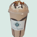 A cup of chocolate shake with whipped cream and pecans.