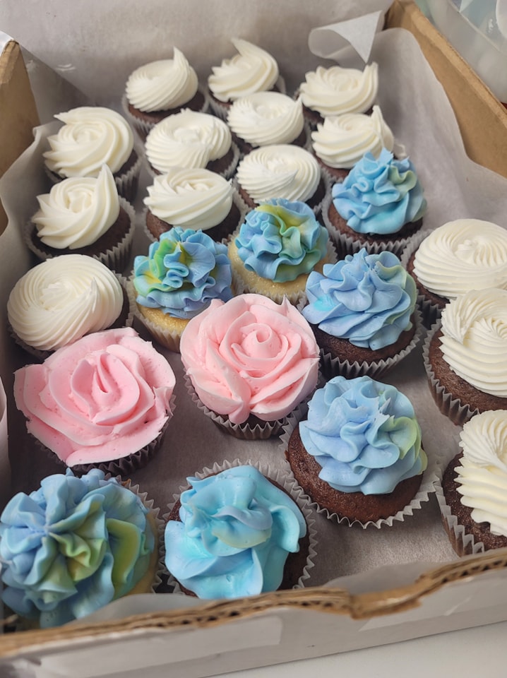A box of cupcakes with blue and white icing.