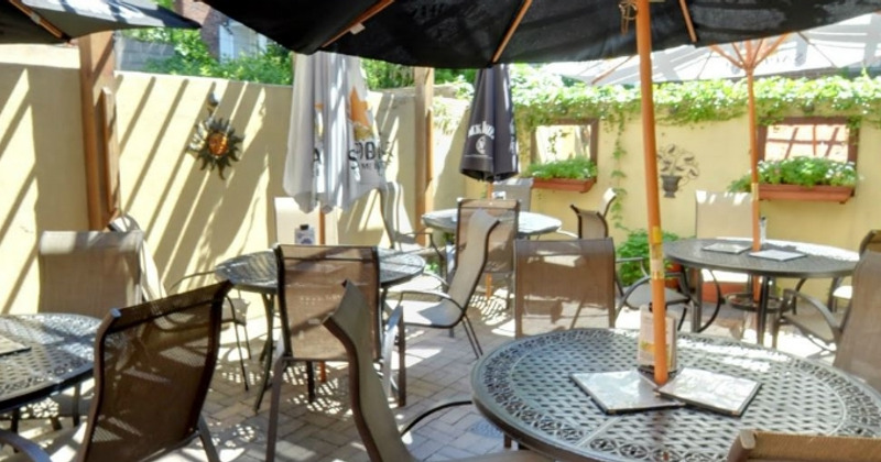 A patio with tables, chairs and umbrellas.