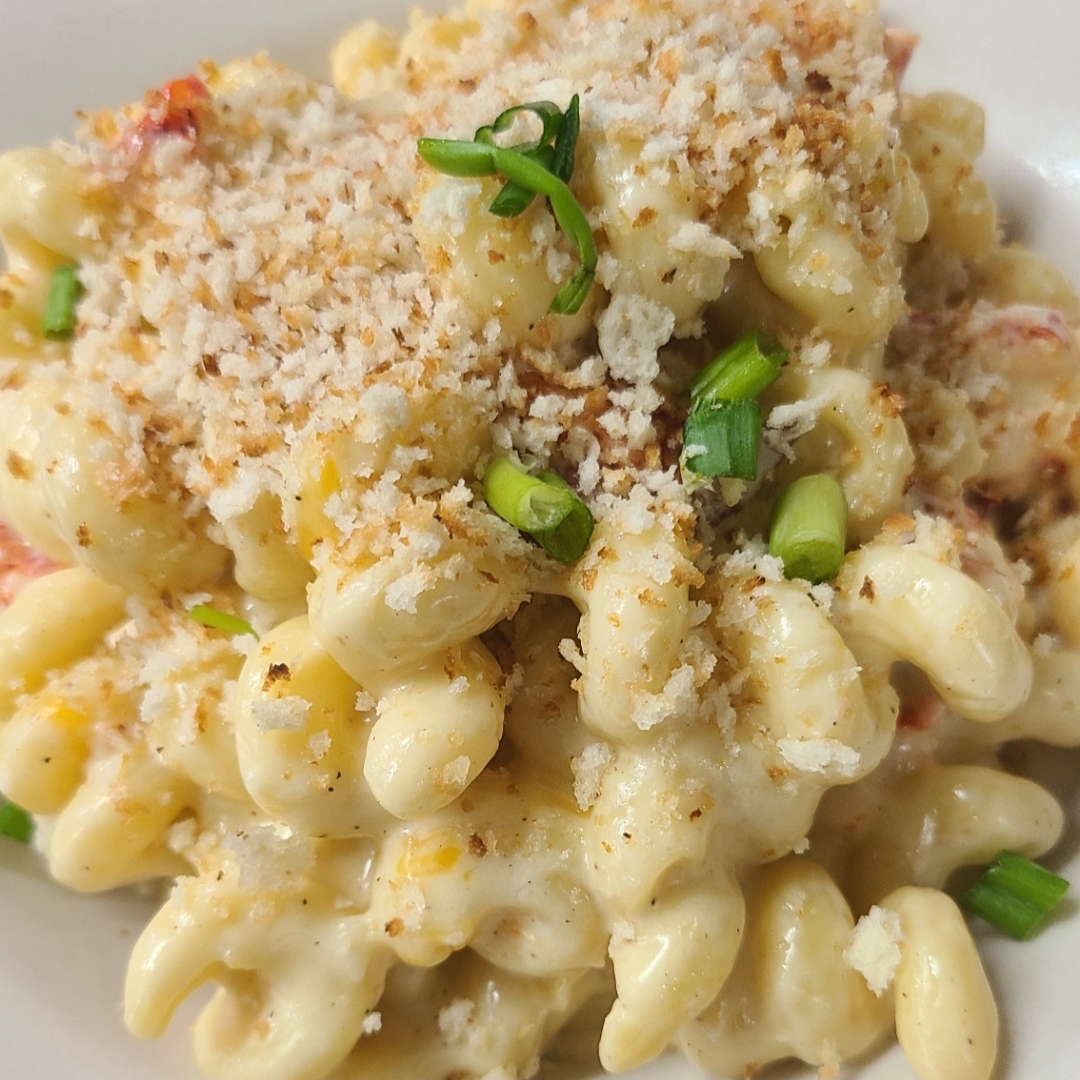A plate of macaroni and cheese with parmesan cheese and green onions.