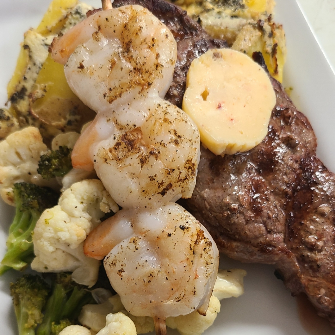 A plate with steak, shrimp, broccoli and cauliflower.