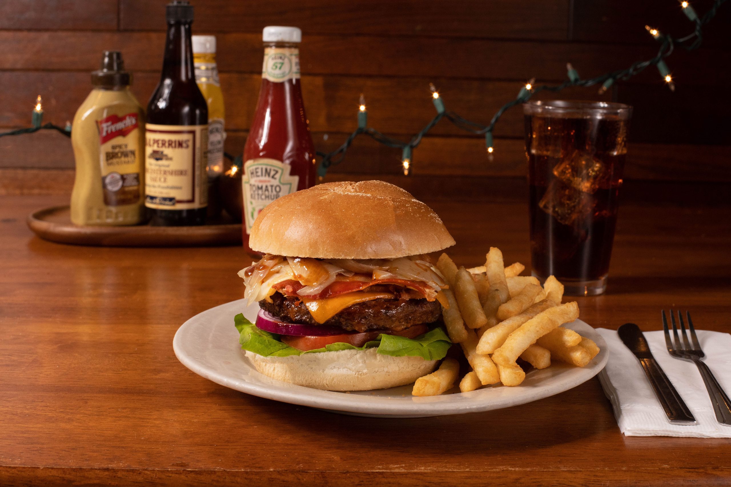 A burger with fries and a drink on a table.