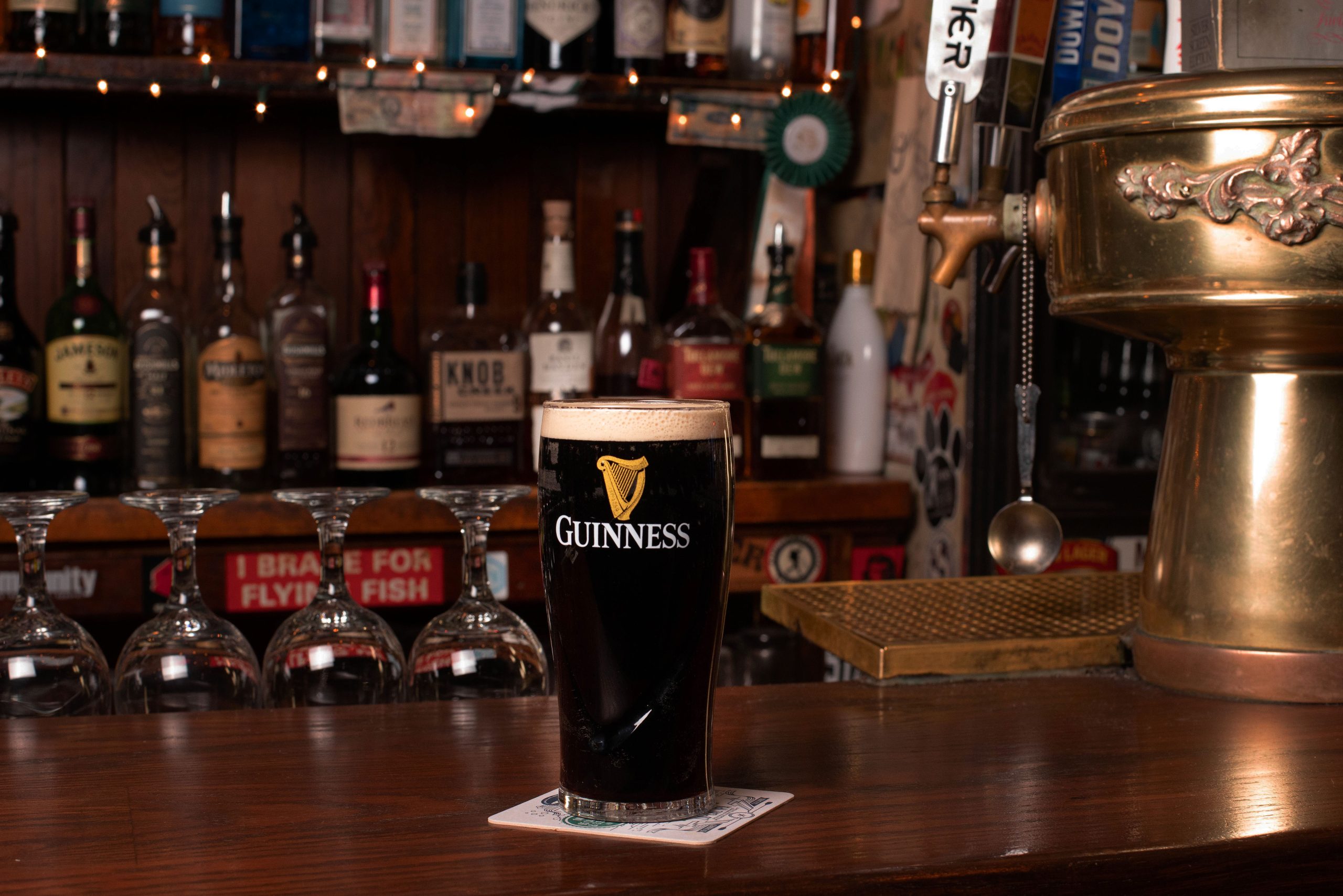 A glass of guinness sitting on a bar.