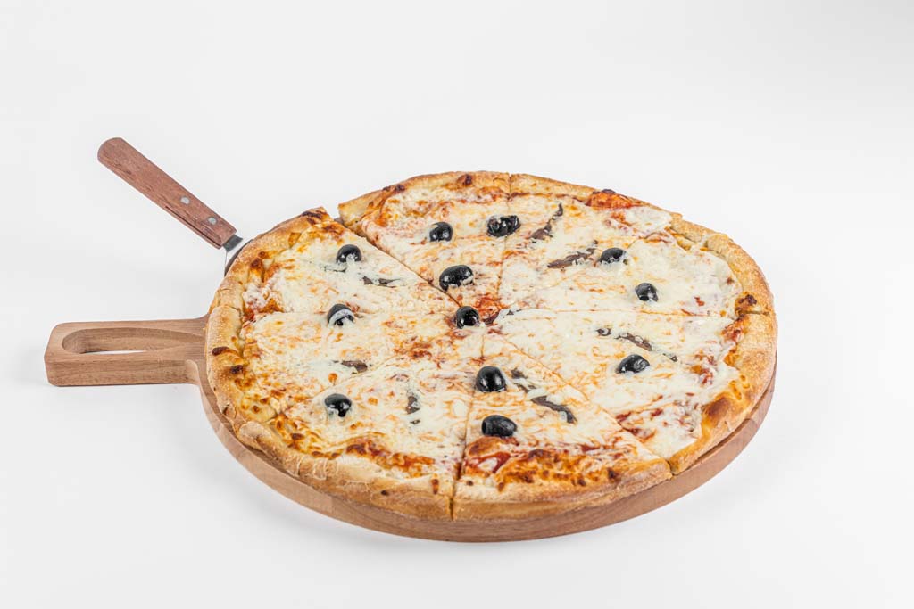 A pizza with olives and cheese on a wooden board.