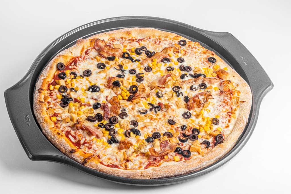 A pizza in a pan on a white background.