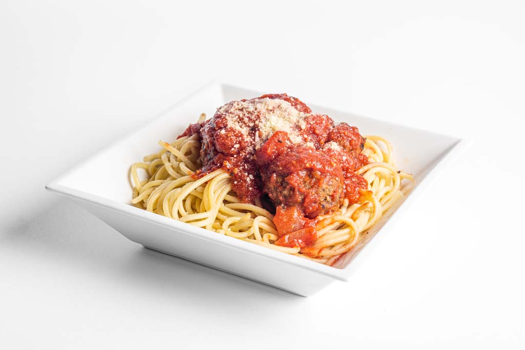 Spaghetti and meatballs in a white bowl on a white background.