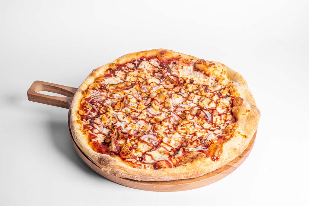 A pizza on a wooden plate on a white background.