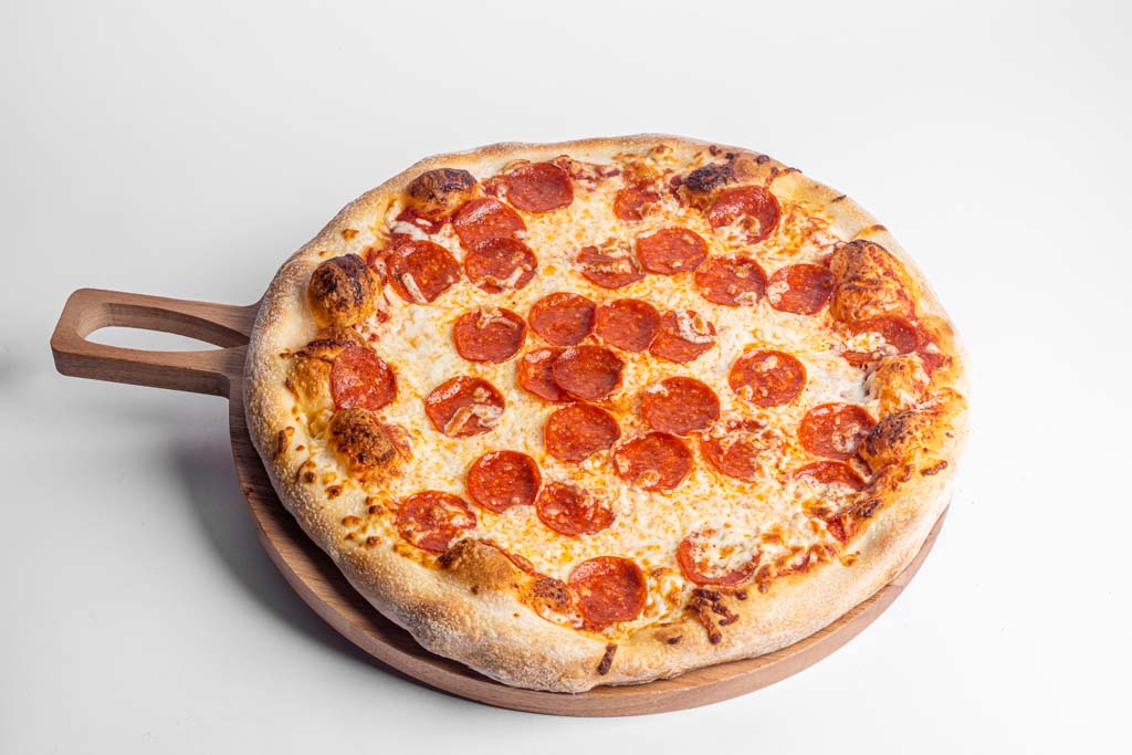 A pepperoni pizza on a wooden plate.