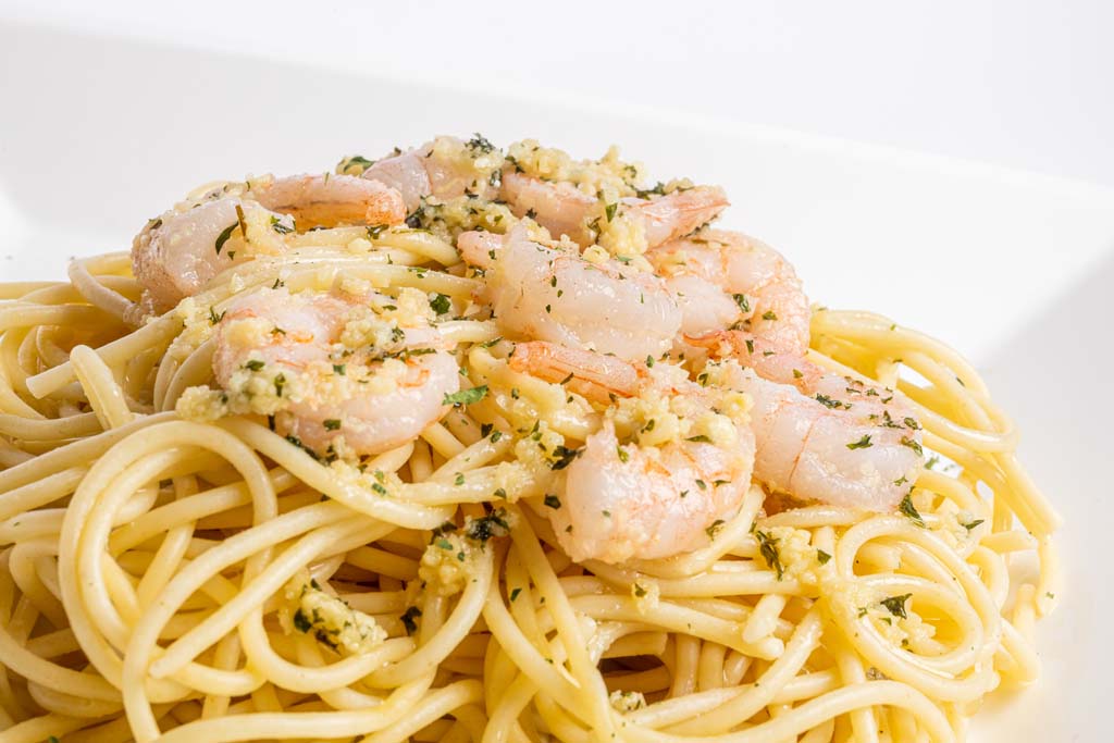 A plate of spaghetti with shrimp and parmesan cheese.