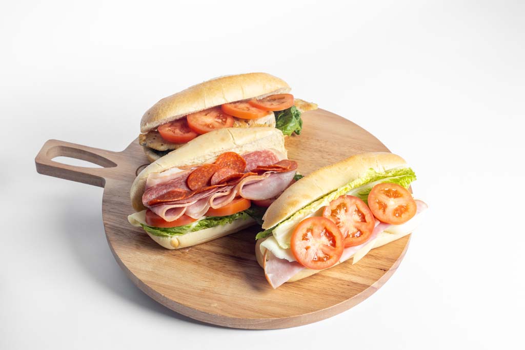 Three sandwiches on a wooden cutting board.