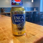A can of inca kola sits on a wooden table.