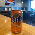 A can of fanta orange soda sits on a table.
