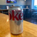 A can of coke sits on a table in a bar.