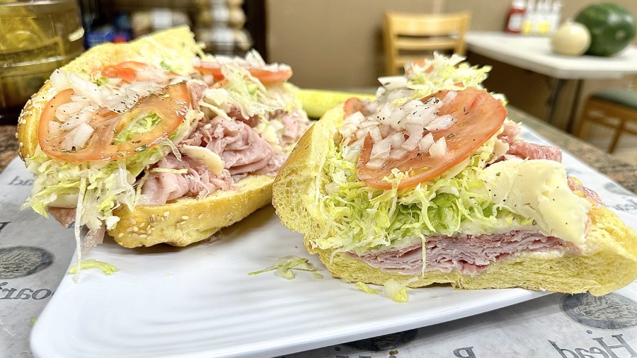 A sandwich with ham, tomatoes and lettuce on a plate.