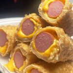 A Plate Of Fried Rolls Filled With Cheese And Hot Dogs.