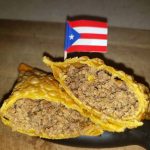A Puerto Rican Flag Toothpick Inserted Into A Ground Beef Filled Fried Plantain Dish, Possibly A Pionono.