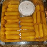 A Tray Of Cheese Sticks With A Side Of Dipping Sauce.