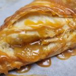 Close Up Of A Flaky Pastry Topped With Caramel, Showing Layers Of Pastry And A Glossy Caramel Glaze.